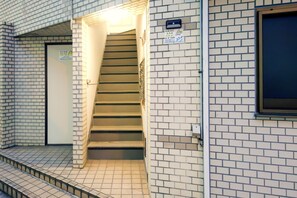 A staircase leading to a door with a sign indicating a hotel entrance. - Ikebukuro 5 Min by Train | 18㎡ for 2 | Double Bed, Kitchen | Fast Wi-Fi (板橋区)