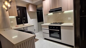 Een moderne keuken met een centraal eiland, inbouwapparatuur en hanglampen.