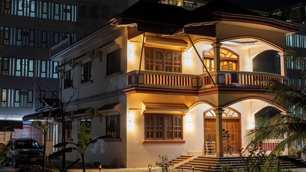 A two-story house with a balcony, a staircase leading to the entrance, and a well-lit front porch. - Teko Paradise and Kitchen (Siem Reap)