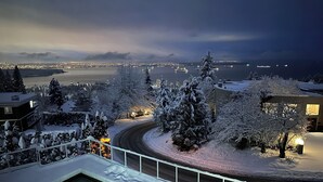 Un paysage enneigé offrant une vue sur une ville et, au loin, sur une étendue d’eau.