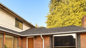 Une maison moderne avec une façade en briques, une porte d’entrée en bois et un escalier menant à l’entrée.