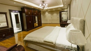 Ein geräumiges Schlafzimmer mit einem großen Bett, einem Kleiderschrank, einem Spiegel und einer Chandelüster.