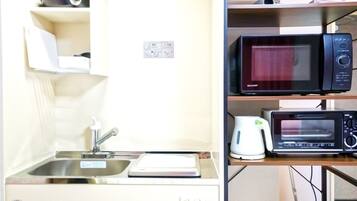 A compact kitchenette with a sink, microwave, toaster, and small refrigerator.