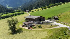 A rural landscape with a large barn, a smaller structure, and a winding road. - Farmhouse apartment with mountain view (Alpbach)