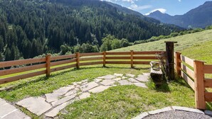 A wooden fence, stone pathway, and a mountainous landscape with a clear sky. - Farmhouse apartment with mountain view (Alpbach)