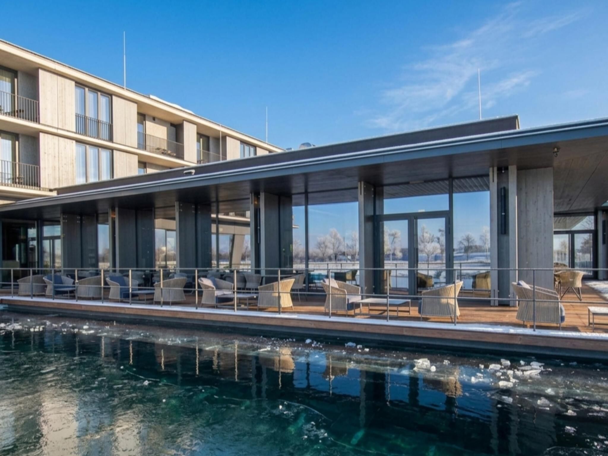 A modern building with a poolside area featuring outdoor seating and large windows.
