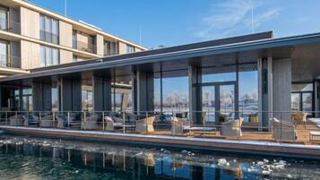 A modern building with a poolside area featuring outdoor seating and large windows.
