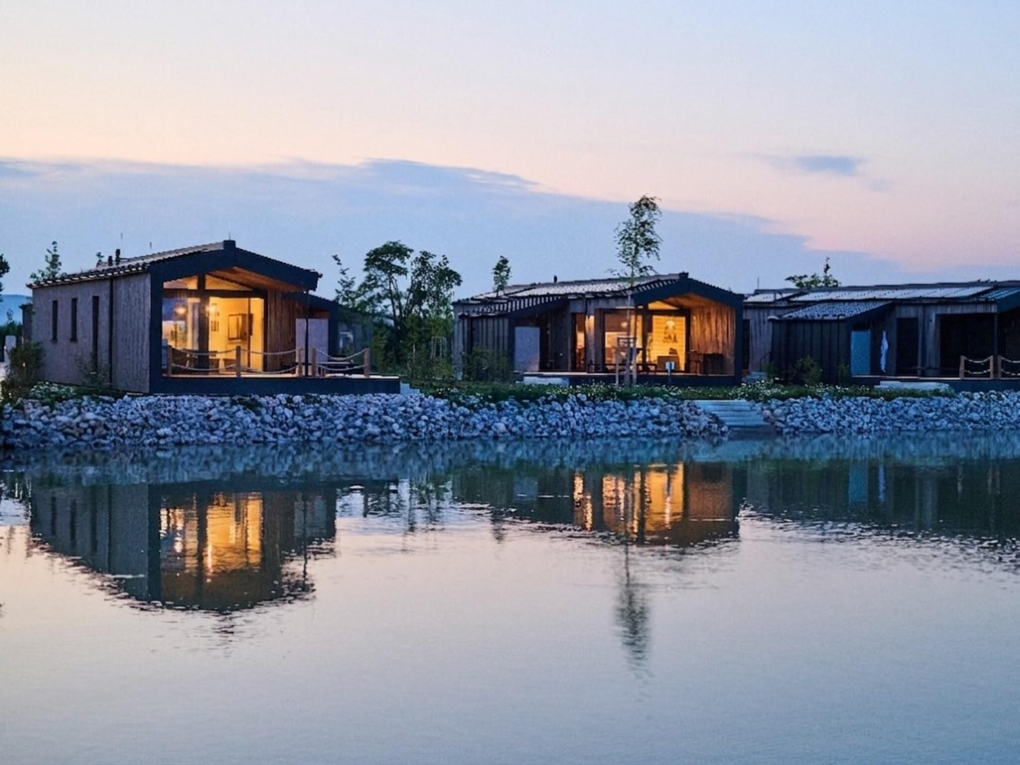 A lakeside resort with two buildings, each featuring a large window and a balcony.