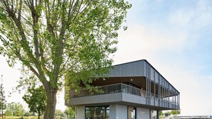 Un bâtiment moderne doté d’un toit plat, de grandes fenêtres et d’un balcon.