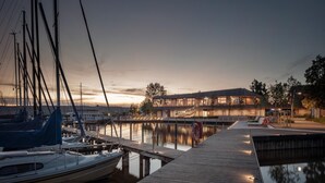 Un port de plaisance où sont amarrés des voiliers et un bâtiment moderne doté de grandes fenêtres.