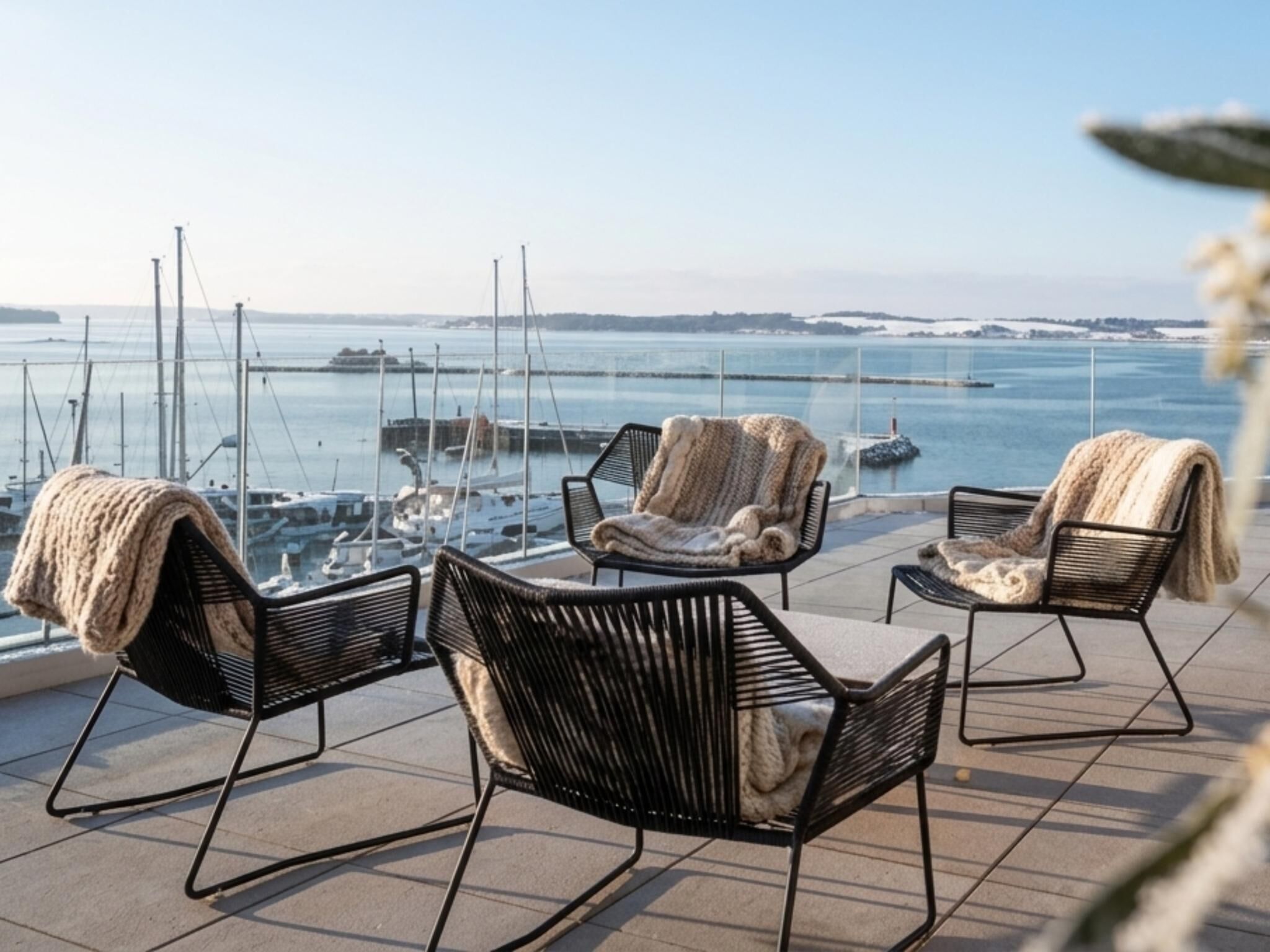 A terrace with outdoor seating and a view of the marina.