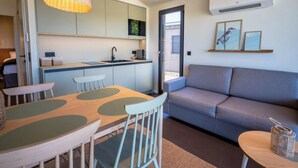 A compact living space with a kitchenette, a dining area with a table and chairs, a sofa, and a small side table. - Wellness guesthouse by a lake with sauna (Breitenbrunn)