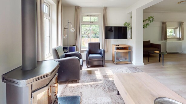Una sala de estar moderna con chimenea, un sofá, un televisor y una mesa de comedor.