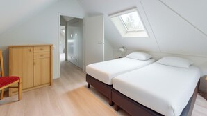 Un dormitorio con dos camas, un armario de madera, una silla y un tragaluz.