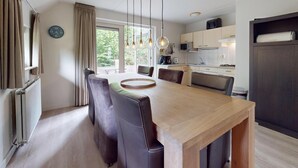 Una cocina moderna con comedor, que incluye una mesa de madera, sillas e iluminación colgante.