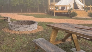 A tented camping area with a fire pit and picnic tables.