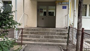 A building entrance with a gated driveway, steps leading to a door, and a sign indicating a non-stop service number. - Imedio Coral Apartment Aviatiei (București)