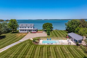 A large house with a swimming pool, a well-maintained lawn, and a view of a large body of water. - Modern Chesapeake Waterfront - Private Pool - Dock (Cambridge)
