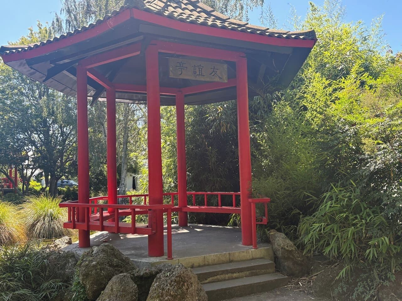 Ein rotes Pavillon mit einem Ziegeldach und einem Schild in einer fremden Sprache.
