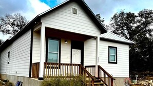 A single-story house with a front porch, a small staircase, and a garage door. - Spring Branch Hill Country Retreat (Canyon Lake)
