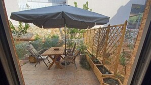 Un patio con tavolo e sedie, una recinzione in legno e fioriere.