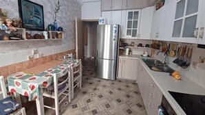 Una cucina compatta con frigorifero, lavello e zona pranzo con tavolo e sedie.