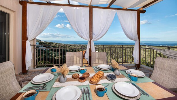 Een terras met een ontbijttafel, met uitzicht op een prachtig panorama.
