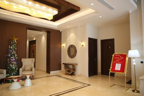 A lobby with a Christmas tree, a reception desk, a mirror, and a welcome sign.