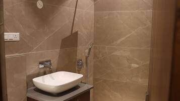Een moderne badkamer met een marmeren wastafel, een douche en een toilet.