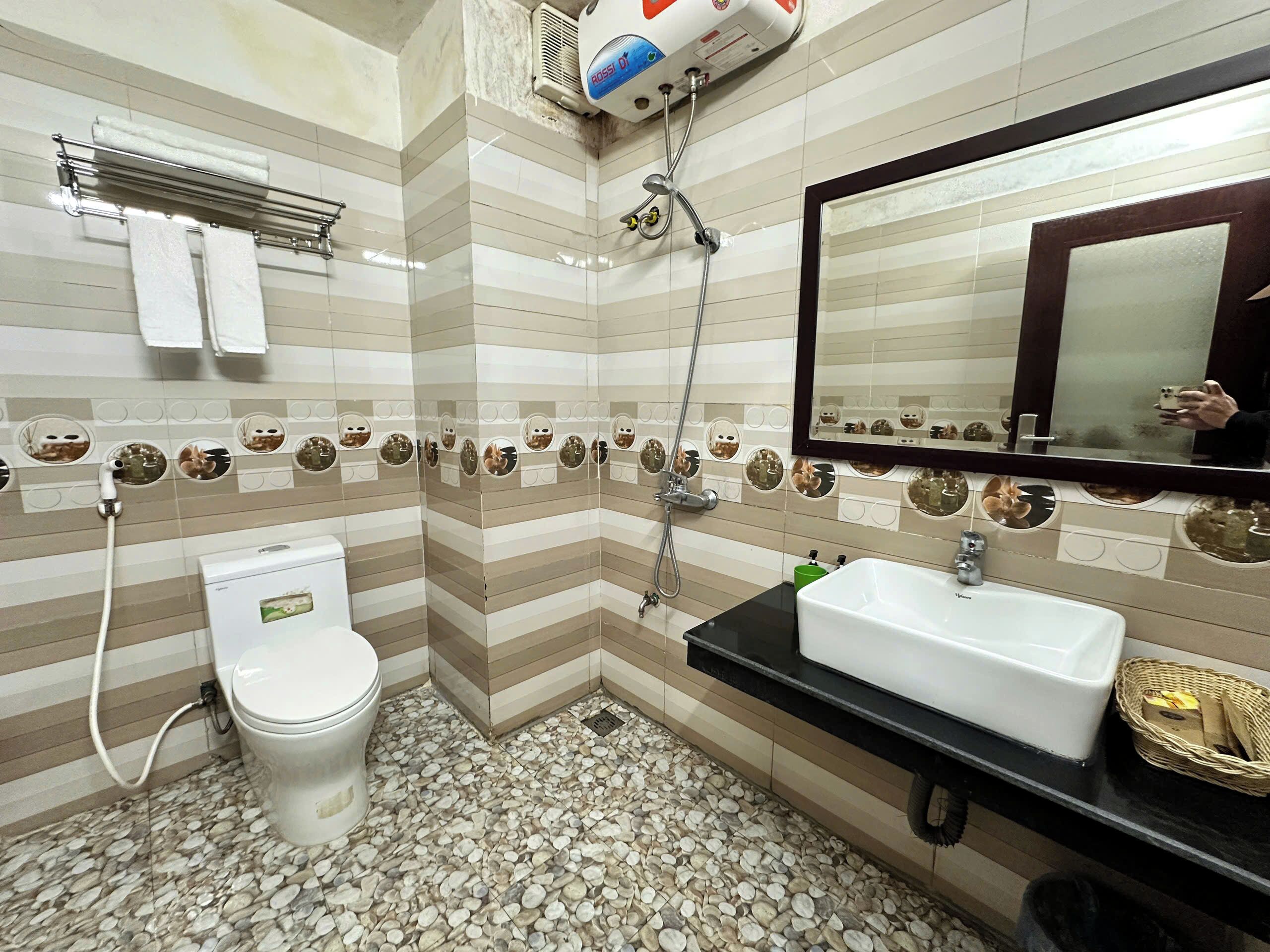 A bathroom with striped tile walls, a toilet, a sink, and a mirror.