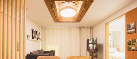 Habitación de hotel con techo de madera, una cama, un sofá, un televisor y un escritorio.