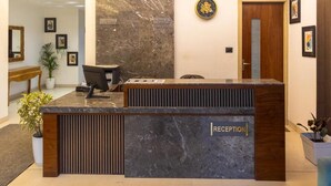 A reception desk with a marble top, a wooden panel, and a sign that reads "RECEPTION". - Divine Peak (Pachmarhi)