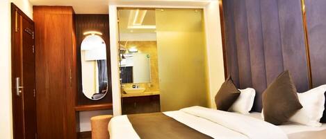 A hotel room with a bed, a wooden wardrobe, a mirror, and a ceiling fan.