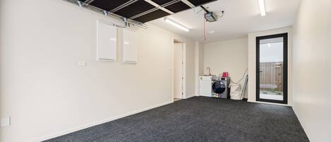 A spacious room with a dark carpet, white walls, and a ceiling with exposed beams.