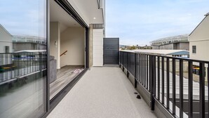 A modern balcony with a glass door, a metal railing, and a view of the street. - Full-sized 3 Bedroom Townhouse - Walking distance to Stadium (Christchurch)