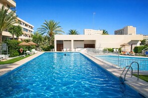 Una piscina al aire libre, sombrillas, sillones reclinables de piscina