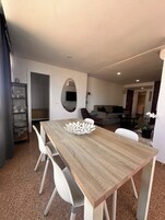 Een moderne woonkamer met een houten eettafel, witte stoelen, een bank en een televisie.