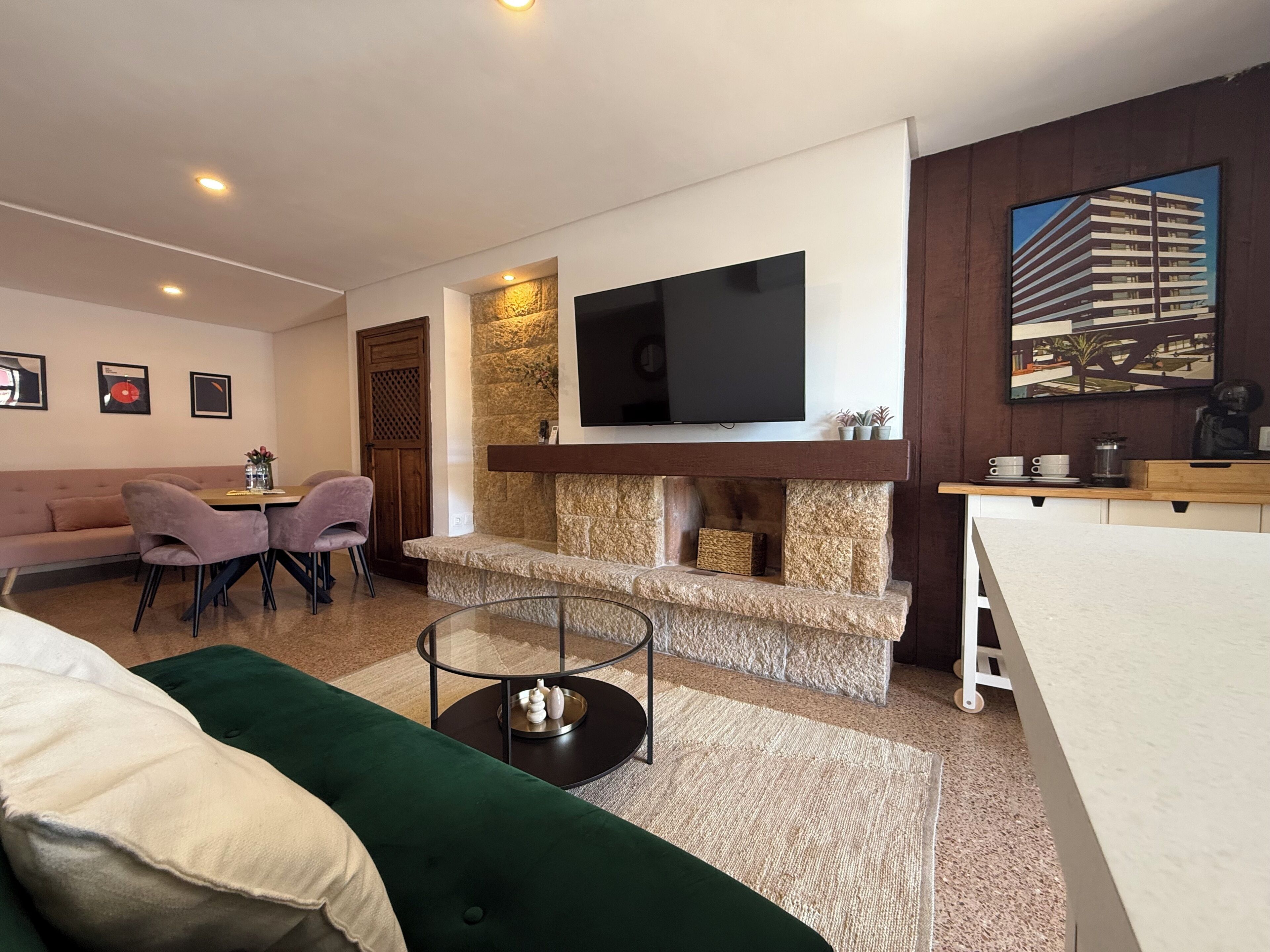 A modern living room with a sofa, chairs, a TV, a fireplace, and a dining area.