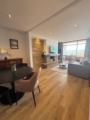 Una sala de estar moderna con chimenea de piedra, un comedor con una mesa redonda y un sofá.