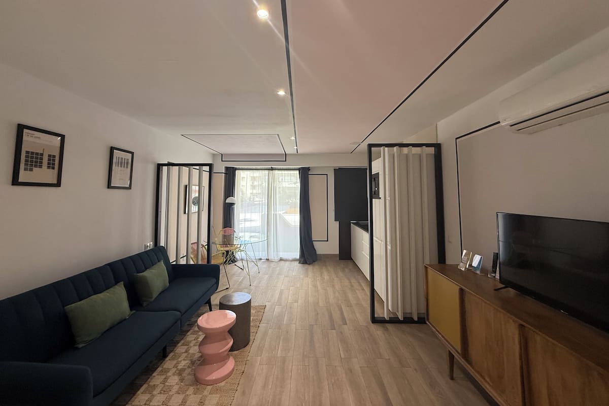 A modern living room with a sofa, a TV, a small table, and a cabinet.