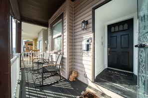A porch with rocking chairs, a cat, and a door with a 'welcome' mat.