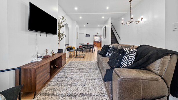 Un salon moderne avec un téléviseur à écran plat, une console en bois et un canapé en cuir marron.