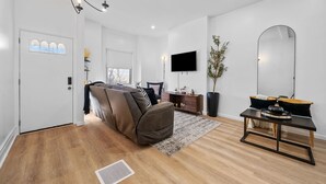Un salon moderne avec un canapé, une table basse, un téléviseur et un grand miroir.