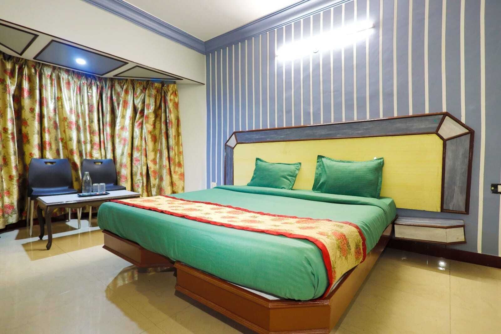 A hotel room with a large bed, a desk with chairs, and a curtain with a floral pattern.