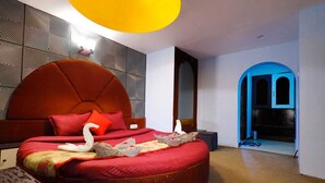 Ein modernes Schlafzimmer mit einem bogenförmigen Bett, einem großen Spiegel und einer außergewöhnlichen Deckenleuchte.
