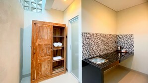 A modern bathroom with a wooden wardrobe, a tiled backsplash, and a black countertop. - Sekar Tunjung Guest House Seminyak (Denpasar)
