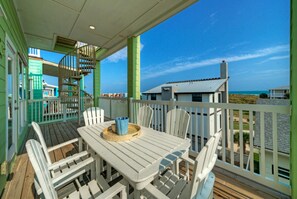 A covered outdoor area with a table and chairs, a spiral staircase, and a view of the ocean and beach houses. - Oceanview Balcony, Private Apartment & Near to the Beach | Beachview 54 (Port Aransas)