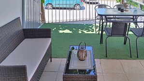 A patio with a wicker sofa, a table with chairs, and a small decorative item on the table. - Georgias house 7 min from Athens airport (Spata-Artemida)