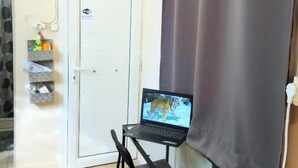 A small room with a laptop on a table, a door, and an air conditioning unit. - Georgias house 7 min from Athens airport (Spata-Artemida)