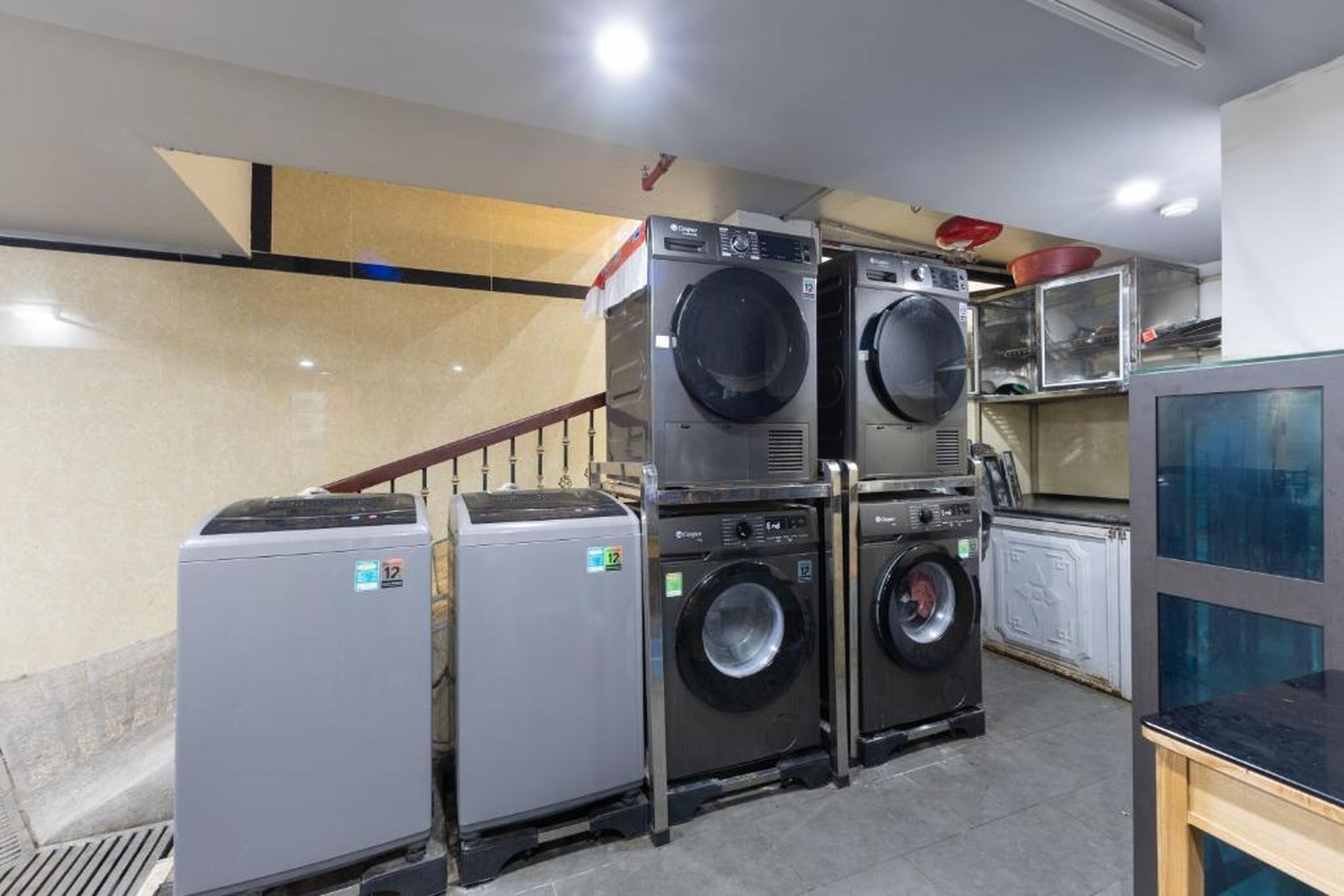 A laundry room with stacked washers and dryers, a small refrigerator, and a microwave.